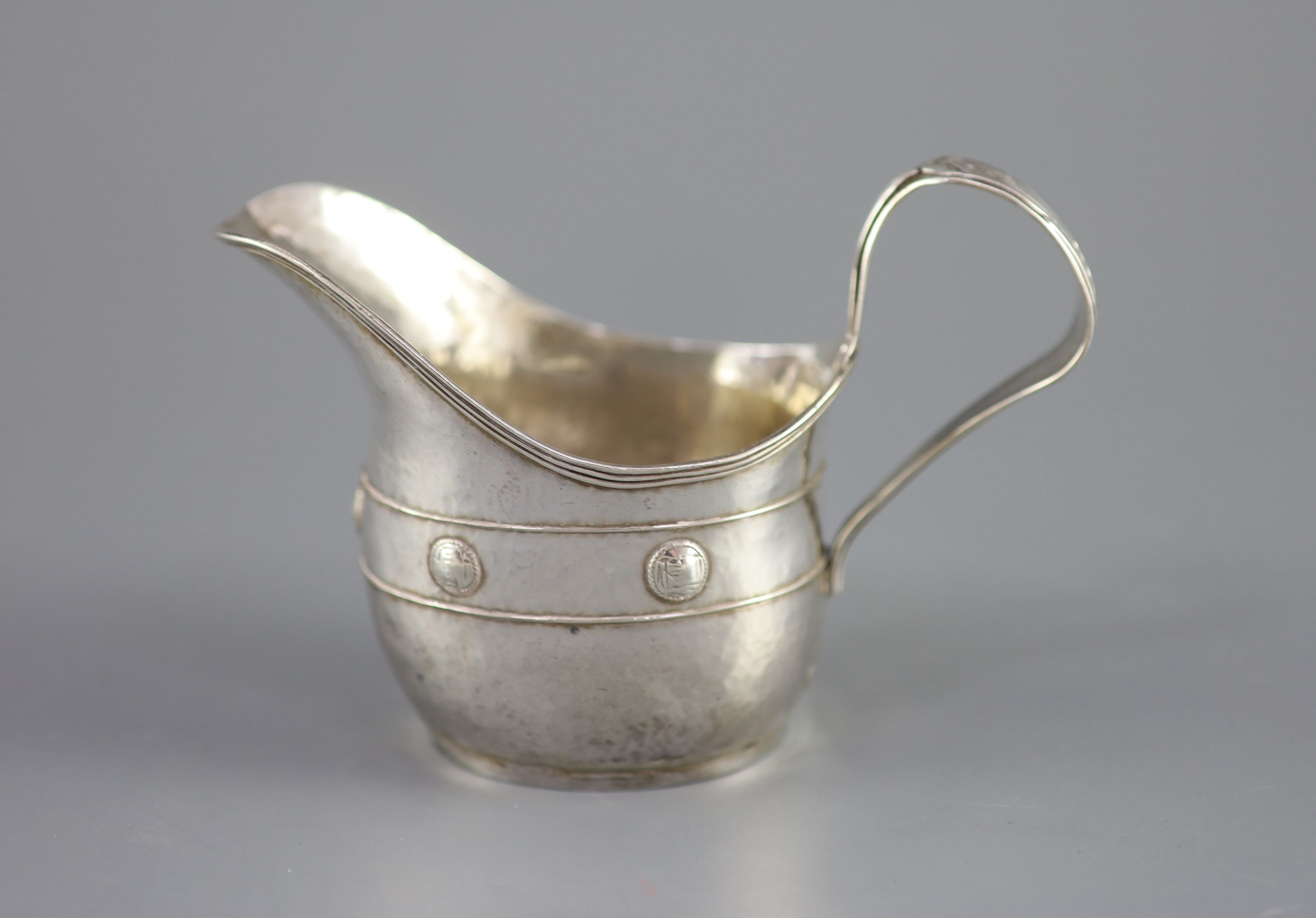 An Edwardian Arts & Crafts planished silver cream jug by John Gatecliff